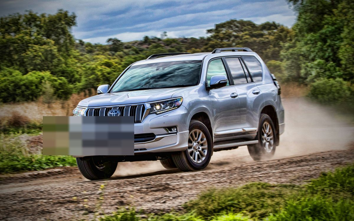 A silver full-size SUV on an unpaved road